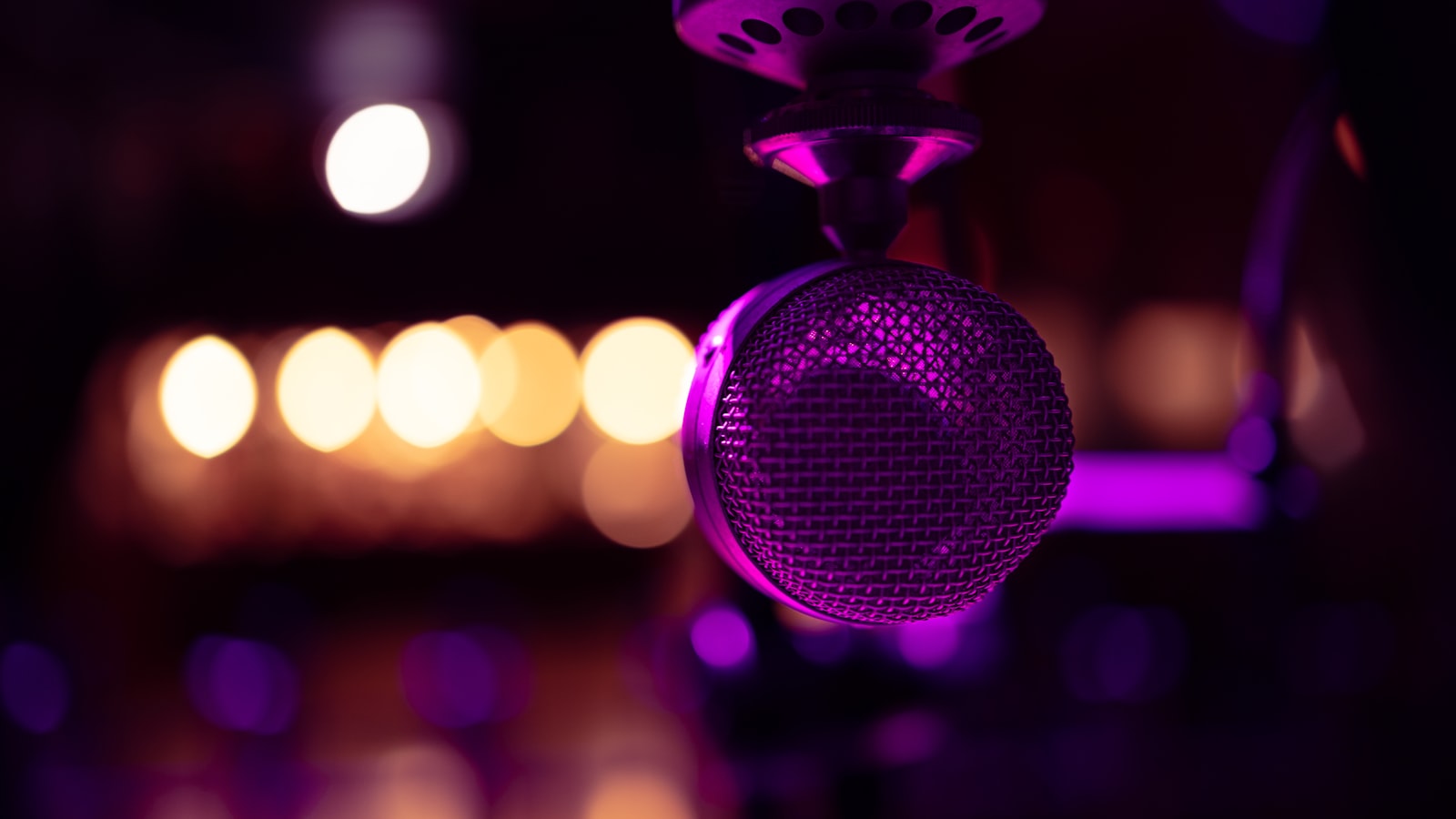 A close-up of a microphone in a dark room lit by purple light