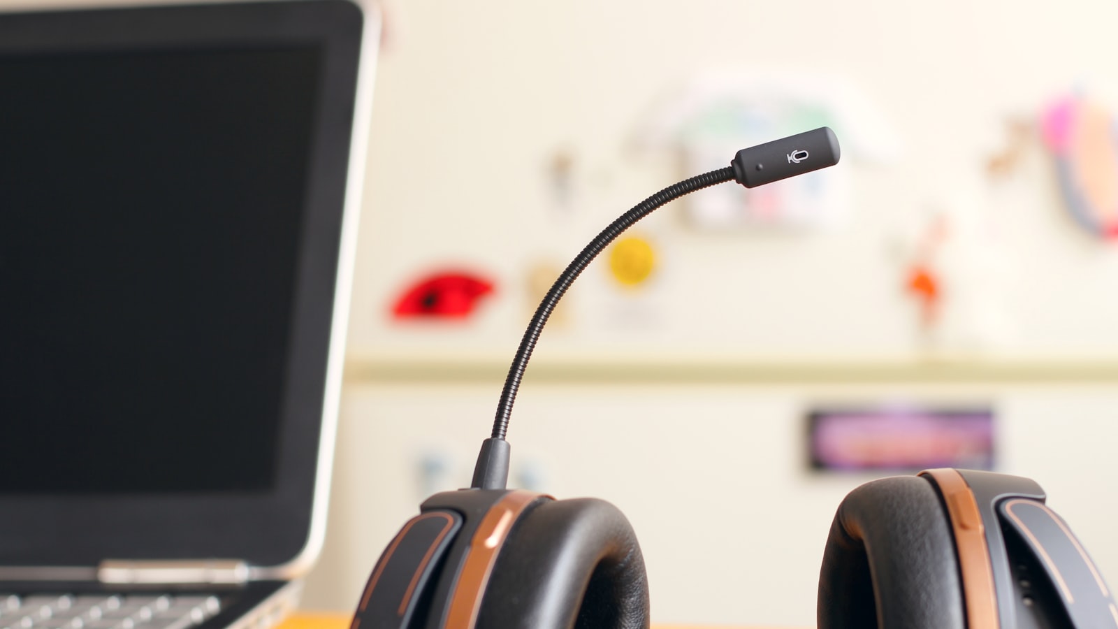 A headset and microphone in front of a laptop on a desk