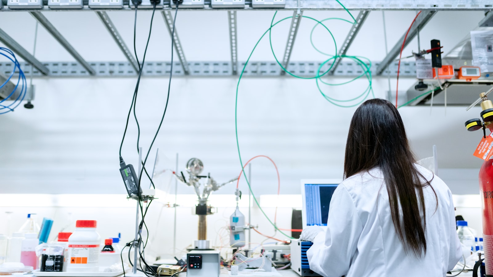 A researcher in a white coat working at a chemistry lab bench