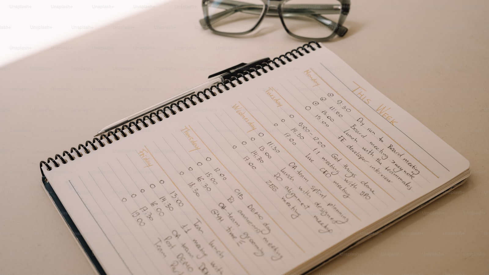 A notebook with a handwritten weekly schedule and a pair of glasses