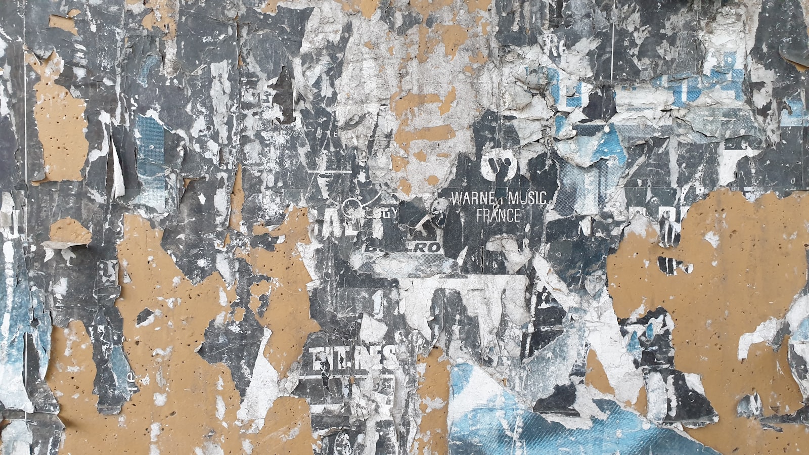 A close-up of a weathered wall with layers of peeling paint