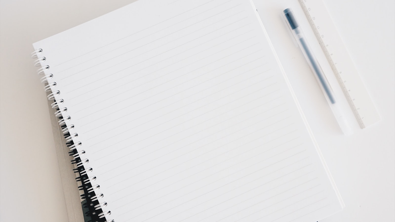 An empty spiral notebook near a keyboard and pen